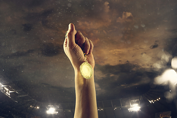 Image showing Award of victory, male hands tightening the medal of winners against cloudy dark sky