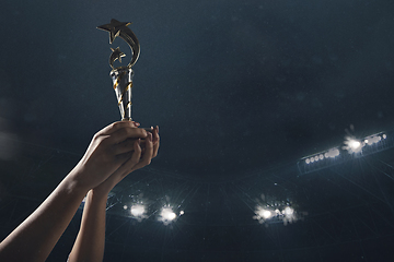 Image showing Award of victory, male hands tightening the cup of winners against cloudy dark sky