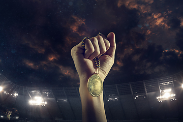 Image showing Award of victory, male hands tightening the medal of winners against cloudy dark sky