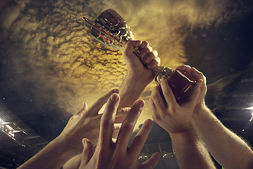 Image showing Award of victory, male hands tightening the cup of winners against cloudy dark sky