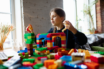 Image showing Girl playing with constructor at home, watching teacher\'s tutorial on laptop. Digitalization, remote education