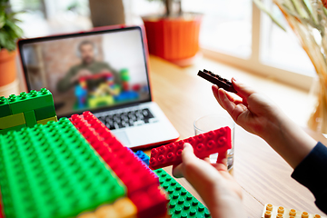 Image showing Girl playing with constructor at home, watching teacher\'s tutorial on laptop. Digitalization, remote education