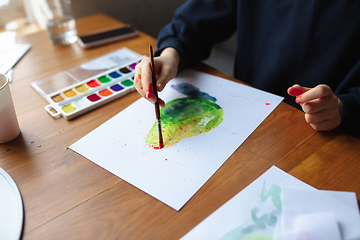 Image showing Girl drawing with paints and pencils at home, watching teacher\'s tutorial on laptop. Digitalization, remote education