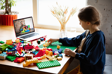 Image showing Girl playing with constructor at home, watching teacher\'s tutorial on laptop. Digitalization, remote education