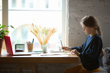 Image showing Girl drawing with paints and pencils at home, watching teacher\'s tutorial on laptop. Digitalization, remote education