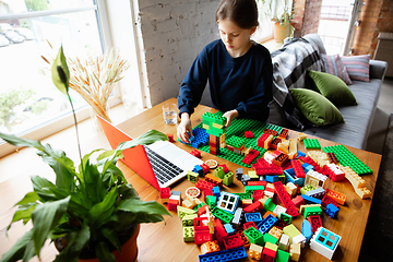 Image showing Girl playing with constructor at home, watching teacher\'s tutorial on laptop. Digitalization, remote education