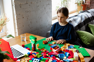 Image showing Girl playing with constructor at home, watching teacher\'s tutorial on laptop. Digitalization, remote education