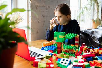 Image showing Girl playing with constructor at home, watching teacher\'s tutorial on laptop. Digitalization, remote education