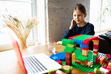 Image showing Girl playing with constructor at home, watching teacher\'s tutorial on laptop. Digitalization, remote education