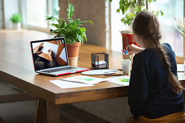 Image showing Girl drawing with paints and pencils at home, watching teacher\'s tutorial on laptop. Digitalization, remote education