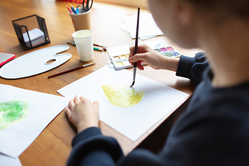 Image showing Girl drawing with paints and pencils at home, watching teacher\'s tutorial on laptop. Digitalization, remote education