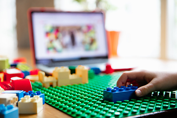 Image showing Girl playing with constructor at home, watching teacher\'s tutorial on laptop. Digitalization, remote education