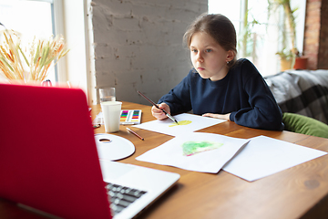 Image showing Girl drawing with paints and pencils at home, watching teacher\'s tutorial on laptop. Digitalization, remote education