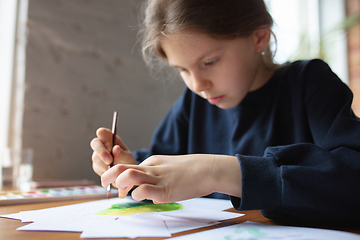 Image showing Girl drawing with paints and pencils at home, watching teacher\'s tutorial on laptop. Digitalization, remote education