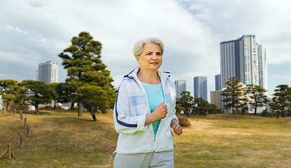 Image showing senior woman running along summer park