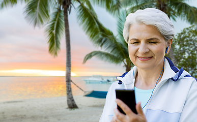 Image showing sporty senior woman with earphones and smartphone