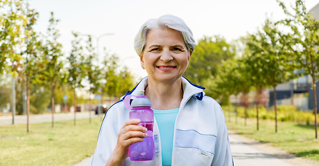 Image showing sporty senior woman with bottle of water at park