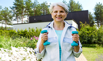 Image showing senior woman with dumbbells exercising at park