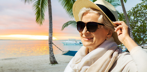 Image showing happy senior woman in sunglasses and hat on beach