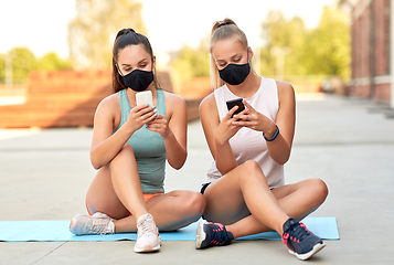 Image showing sporty women or friends with smartphone on rooftop