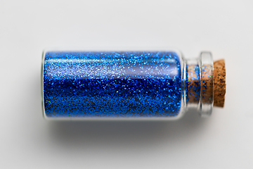 Image showing blue glitters in bottle over white background