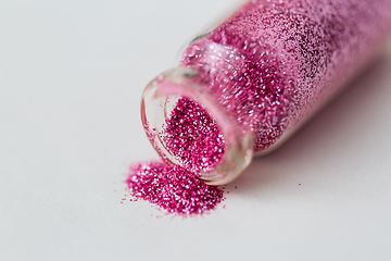 Image showing pink glitters poured from small glass bottle