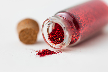 Image showing red glitters poured from small glass bottle