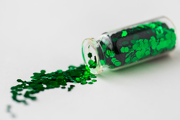 Image showing green glitters poured from small glass bottle