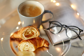 Image showing croissants, cup of coffee, book and glasses in bed