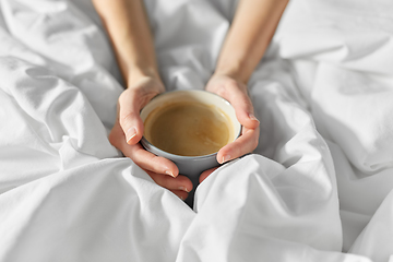 Image showing hands of woman with cup of coffee in bed