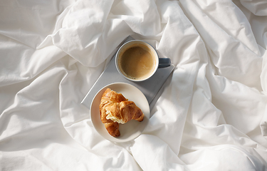 Image showing croissants, cup of coffee and book in bed at home