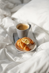 Image showing croissants, cup of coffee and book in bed at home