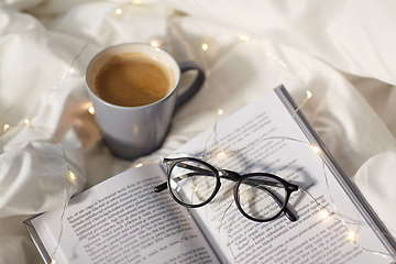Image showing cup of coffee, book, glasses and garland in bed