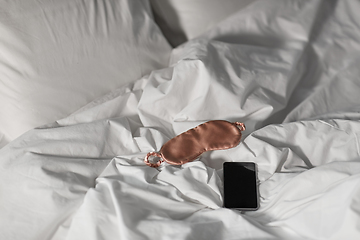 Image showing smartphone and eye sleeping mask in bed at night