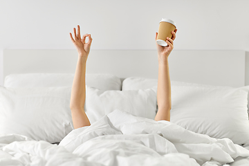 Image showing woman with cup of coffee lying in bed showing ok