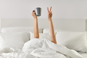 Image showing woman with coffee lying in bed showing peace