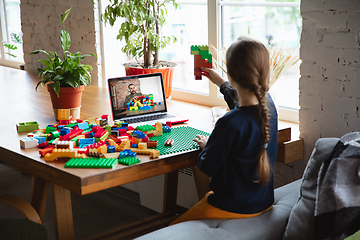 Image showing Girl playing with constructor at home, watching teacher\'s tutorial on laptop. Digitalization, remote education