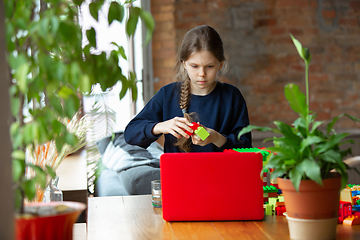 Image showing Girl playing with constructor at home, watching teacher\'s tutorial on laptop. Digitalization, remote education