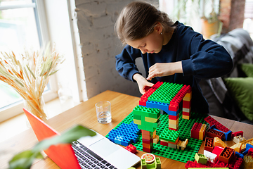 Image showing Girl playing with constructor at home, watching teacher\'s tutorial on laptop. Digitalization, remote education