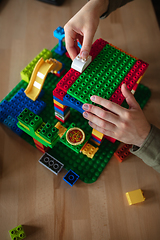 Image showing Close up of male hands playing with colorful plastic constructor on wooden background