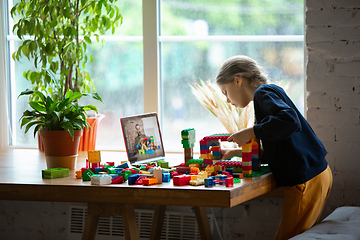 Image showing Girl playing with constructor at home, watching teacher\'s tutorial on laptop. Digitalization, remote education