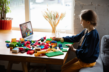 Image showing Girl playing with constructor at home, watching teacher\'s tutorial on laptop. Digitalization, remote education