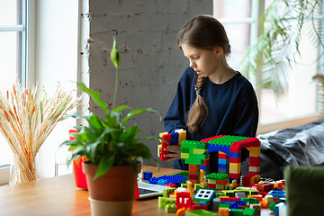 Image showing Girl playing with constructor at home, watching teacher\'s tutorial on laptop. Digitalization, remote education