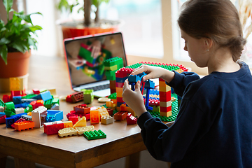 Image showing Girl playing with constructor at home, watching teacher\'s tutorial on laptop. Digitalization, remote education