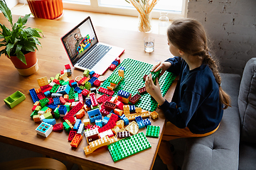 Image showing Girl playing with constructor at home, watching teacher\'s tutorial on laptop. Digitalization, remote education