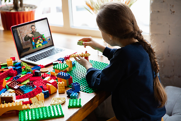 Image showing Girl playing with constructor at home, watching teacher\'s tutorial on laptop. Digitalization, remote education