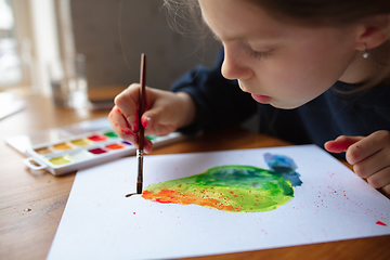 Image showing Girl drawing with paints and pencils at home, watching teacher\'s tutorial on laptop. Digitalization, remote education