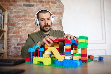 Image showing Man giving online lesson with constructor at home. Recording teacher\'s tutorial on camera for kids. Digitalization, remote education