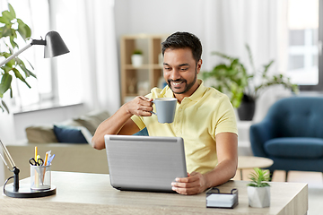 Image showing man with laptop drinking coffee at home office