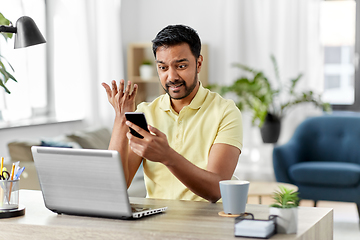 Image showing angry indian man with smartphone at home office